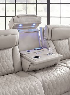 the back seat of a white leather couch with an electronic device in it's center