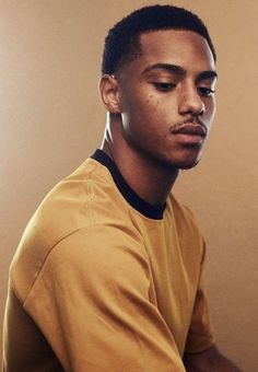 a close up of a person wearing a yellow shirt and holding a cell phone in his hand