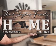 a man holding up a wooden sign that says the claffins family home