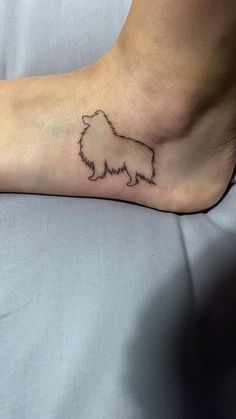 a small dog tattoo on the foot of a person's leg, which is sitting on a bed