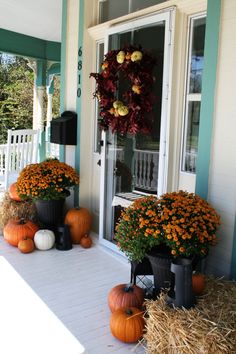 some pumpkins and hay are sitting on the porch