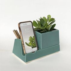 a cell phone is sitting in a planter with some gold sticks sticking out of it