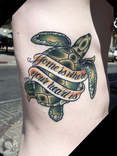 a tattoo on the leg of a woman with a sea turtle and ribbon around it