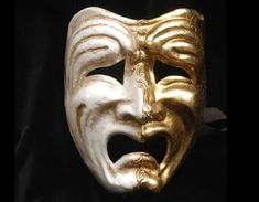 a gold mask with an open mouth on a black background