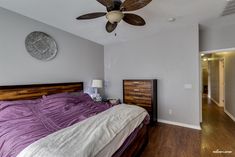 a bed room with a neatly made bed and a ceiling fan