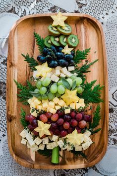 a christmas tree made out of grapes, kiwis and cheese on a wooden platter