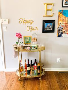 a bar cart filled with liquor bottles on top of a hard wood floor next to a white wall