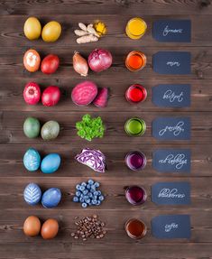 an array of different colored eggs on a wooden table next to some fruit and vegetables