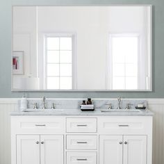 a bathroom with two sinks and a large mirror on the wall above it, in front of a window