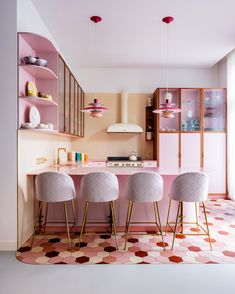 a kitchen with pink counters and chairs in front of a counter top that has three lights hanging from the ceiling