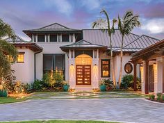 a large white house with palm trees in the front yard and landscaping on both sides