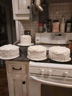 three white cakes sitting on top of a kitchen counter next to an oven and microwave