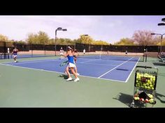 two women playing tennis on a court with rackets and balls in front of them