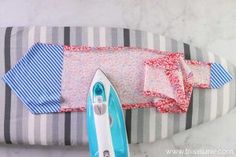 an ironing board and some ties laying on a striped pillow next to each other