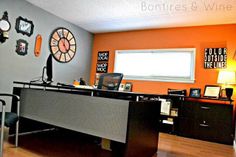 an office with orange walls and clocks on the wall, along with a desk in front of a window