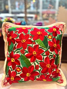 a red flowered pillow sitting on top of a table