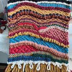 a multicolored woven rug is displayed on a table with other items in the background