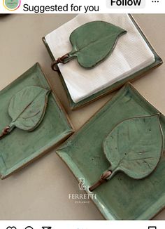 three green plates with leaves on them sitting on top of a table next to each other