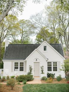 a white house surrounded by trees and flowers