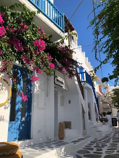 a white building with blue doors and pink flowers