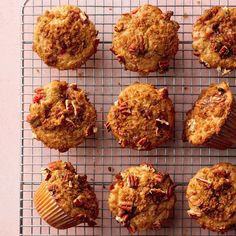 twelve muffins on a cooling rack with pecans in the middle and crumbs all over them