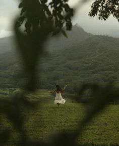 a woman in a white dress standing on top of a lush green field