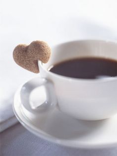 a cup of coffee with a heart shaped lollipop sticking out of it's side