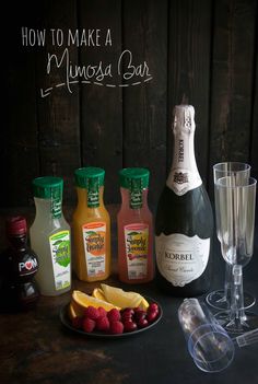 bottles and glasses are sitting on a table with fruit, juice, and other condiments