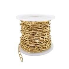 a spool of gold colored wire on a white surface with a chain attached to it