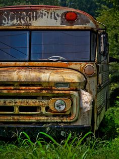 an old rusty school bus sitting in the grass