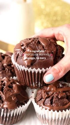 chocolate muffins with frosting being held by a woman's hand on a white plate