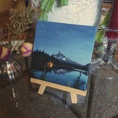 an easel with a painting on it next to flowers and candles