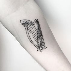 a black and white photo of a tattoo with a harp on it's arm