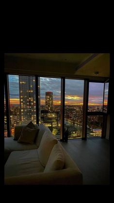 a couch sitting in front of a window with the city lights lit up behind it