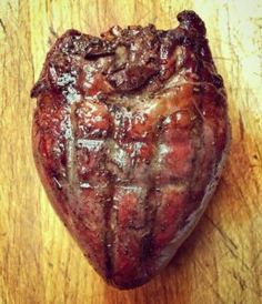 a heart shaped piece of meat sitting on top of a wooden table