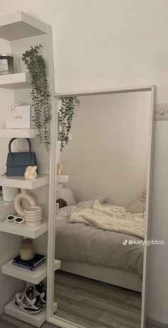 a bedroom with a bed, mirror and shelves on the wall next to each other