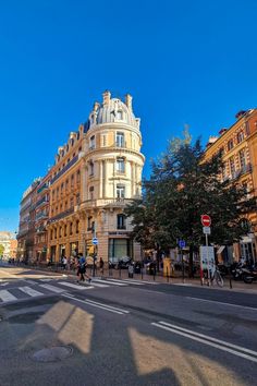 an empty street in the middle of a city with buildings on both sides and people riding bikes