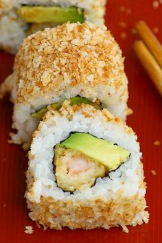 two pieces of sushi on a red plate with chopsticks next to it