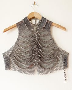 "Falconiere ribcage vest. Halter vest with chainmail base and 8 rows of draped double link chunky chain. Small ring chainmail collar bordered in bordered by chain. Notched center front hem. Lobster claw clasps at high and low back neck with adjustable chains. Lobster claw clasps at center back and straps with adjustable chains. Stainless steel chainmail in two ring sizes. Silver-tone plated steel chain Made by me in the USA. 3 - 6 weeks, but please let me know if you need it sooner. If you need Chainmail Crochet, Chainmail Vest, Professional Punk, Shoulder Jewellery, Chainmail Clothing, Shoulder Jewelry, Chainmail Jewelry, Chain Maille Jewelry, Collar Chain