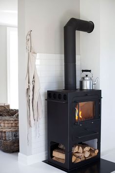 a black stove sitting inside of a kitchen next to a wall mounted heater on top of a white tiled floor