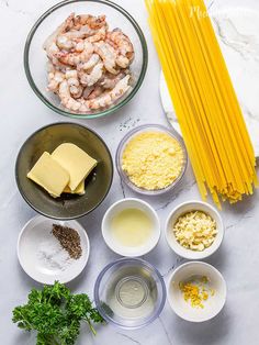 ingredients to make shrimp pasta laid out on a white marble counter top, including parmesan cheese and garlic