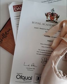 a pair of ballet shoes sitting on top of an official document with the royal academy logo