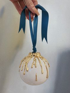 a hand holding a glass ornament with blue ribbon