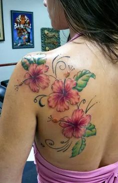 a woman wearing a pink dress with flowers on her shoulder and chest tattooing it's back