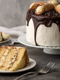 a cake with white frosting and chocolate drizzled on top, sitting next to another cake