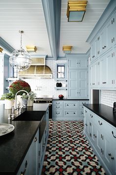 a kitchen with blue cabinets and black counter tops, an area rug on the floor