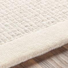 a close up view of a white rug on a wooden floor with wood grained floors