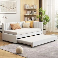 a white couch sitting on top of a wooden floor next to a book shelf filled with books