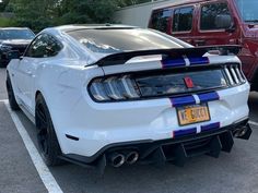 the rear end of a white mustang parked in a parking lot