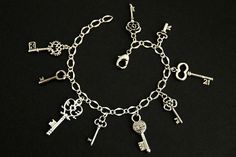 a silver bracelet with keys and key charms on it's sides, all in different shapes and sizes